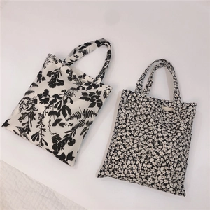 Detail of minimalist black and white cotton tote bags with floral and tropical leaf prints