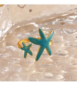 Macro detail of 18K gold starfish open ring with blue enamel on ocean ripple base