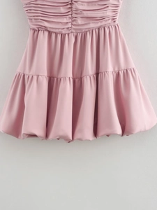 Close-up of pink balloon-style mini dress featuring pleated silk fabric layers