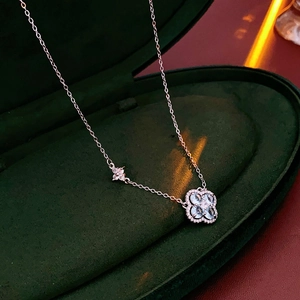 Gros plan d'un collier trèfle argenté avec zircon bleu dans son écrin en velours