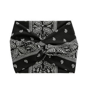 Detail of wide black yoga headband with white paisley print and center twist knot detail