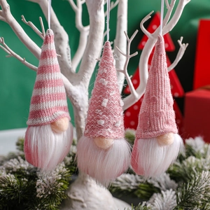 Three pink knitted Christmas gnomes with white faux fur beards hanging on decorative branches