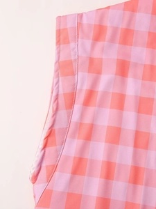 Close-up of pink and orange plaid fabric with neat stitching on casual vest