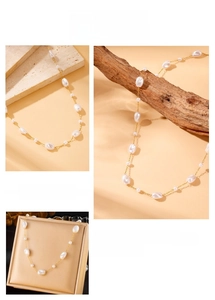 Detail of baroque pearl gold chain necklace displayed on stone and wood surfaces