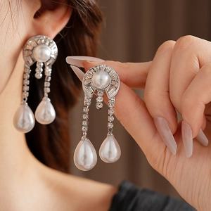 Detail of silver drop earrings featuring a large pearl surrounded by crystals and pendants