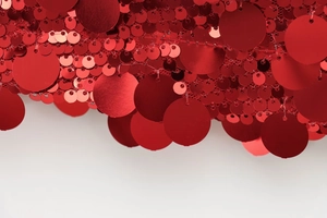 Macro shot of layered red sequins in various sizes on mesh fabric for sewing