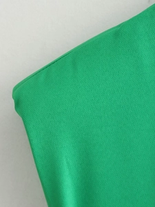 Gros plan du tissu de robe sans manches vert vif montrant une maille dense