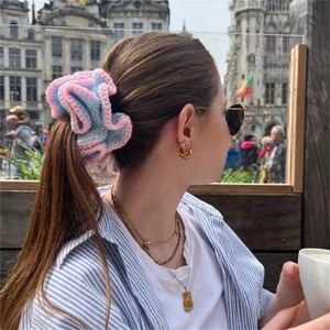 Detail of pink and blue crochet ruffle scrunchie on a ponytail with a knit texture