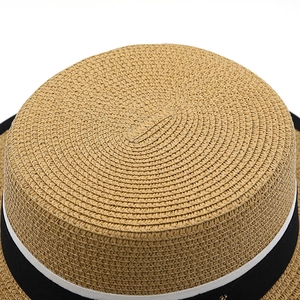 Dettaglio del cappello boater in paglia con trama intrecciata e nastro grosgrain a righe