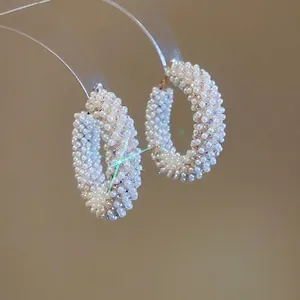 Elegant silver hoop earrings with white pearls and iridescent beads on display