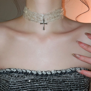 Gros plan du ras-du-cou en dentelle avec pendentif croix argentée et sequins brillants