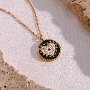 Gros plan d'un pendentif en or avec cœur en émail noir et points bleus sur collier