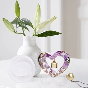 Macro detail of heart-shaped resin mold with floral pattern and gold metal bell