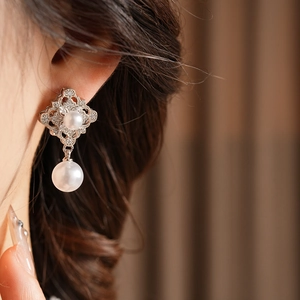 Close-up of vintage hollow diamond earrings with pearls worn by a model in soft lighting