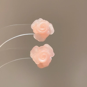 Macro view of light pink resin flower stud earrings with a translucent floral finish