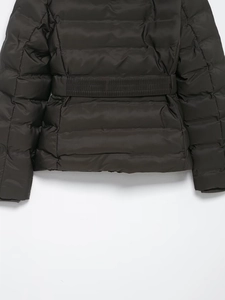 Detailed close-up of dark brown quilted jacket with elastic waist and windproof fabric