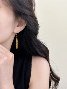 Close-up of gold coin tassel earrings on model showing elegant retro Chinese style