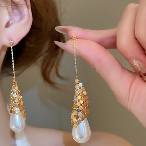 Detailed macro view of 18k gold plated drop earrings with white pearl pendants