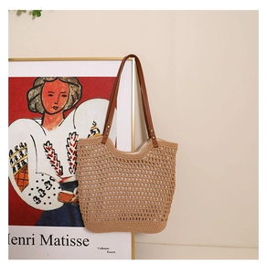 Detail of hollow-out khaki woven bag with brown leather straps and metal rivets