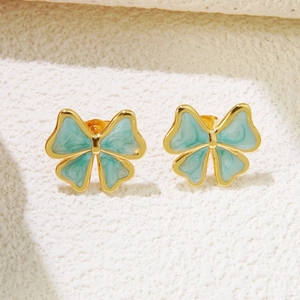 Gros plan de boucles d'oreilles nœuds dorées avec texture marbre bleu clair sur blanc