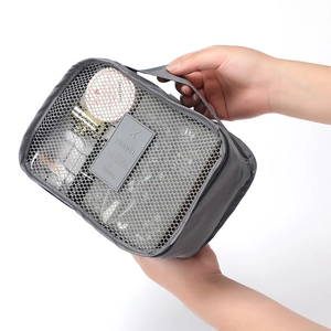 Gray mesh travel storage bag with handle, portable organizer for clothes and shoes in detail view.