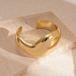 Detailansicht eines skulpturalen goldenen Armreifs mit polierter Oberfläche