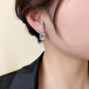 Gros plan de boucles d'oreilles courbées en argent avec zircons étincelants sur modèle