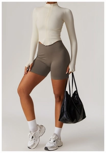 Gros plan d'une veste de yoga zippée blanc cassé avec passe-pouces et short de sport gris