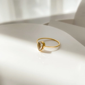 Detailed macro shot of a pear-shaped rhinestone set on a slim gold-tone band