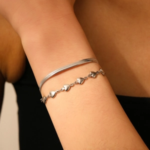 Gros plan de bracelets double couche en acier inoxydable argenté avec chaînes serpent et cœur