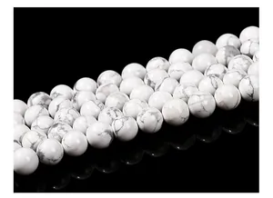 Macro shot of natural white turquoise beads with grey marble texture on black reflective surface