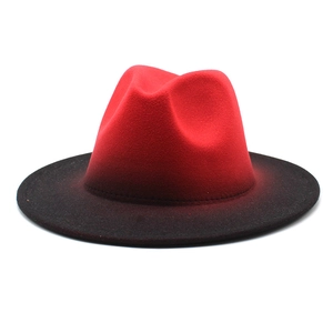 Macro view of gradient red and black felt fedora hat with wide brim showing texture