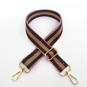 Detail of adjustable colorful striped canvas bag strap with golden metal lobster clasps
