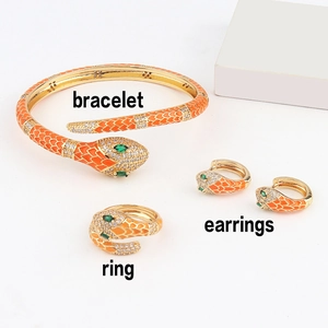 Detail of orange enamel snake jewelry set with gold plating and green gemstone eyes