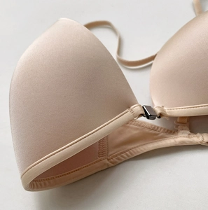 Close-up of front buckle closure and smooth nude fabric on triangle cup bra