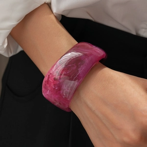 Detail of wide magenta resin bangle with marble texture worn with a white shirt