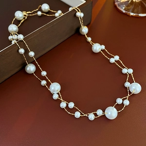 Close-up of gold-plated double-layer necklace with elegant pearls on brown leather background