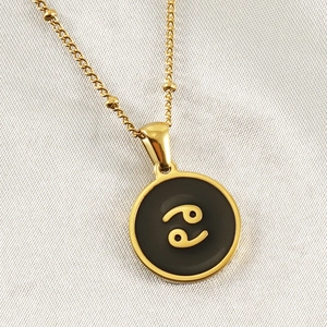 Macro shot of gold constellation necklace with black Cancer zodiac pendant and beaded chain