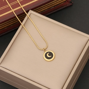 Macro detail of gold moon necklace with black enamel pendant on a jewelry box
