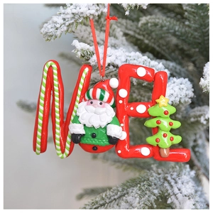 Macro detail of NOEL clay Christmas ornament with Santa and tree on snowy pine branch