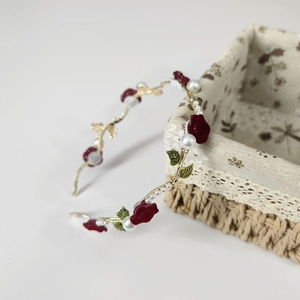 Detail of velvet red roses and white pearls on a gold branch hairband with lace background