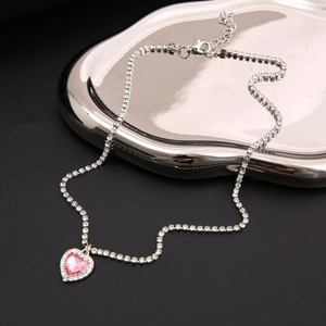 Macro shot of pink heart gemstone pendant with silver-toned crystal encrusted chain