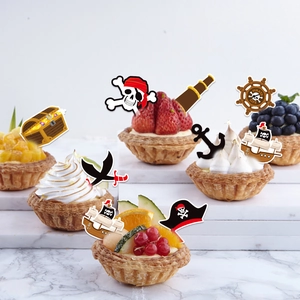 Pirate theme party cake toppers set with skull and ship designs on marble background