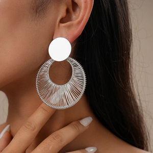 Macro shot of silver woven fan-shaped earrings worn by a model in soft light