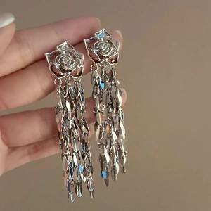 Détail de boucles d'oreilles rose argentée avec glands en feuilles et cristaux brillants