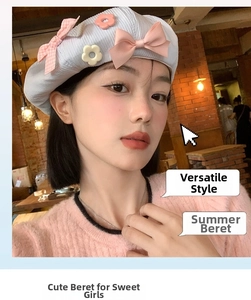 Close-up of light blue beret featuring delicate pink bows and floral details on textured fabric