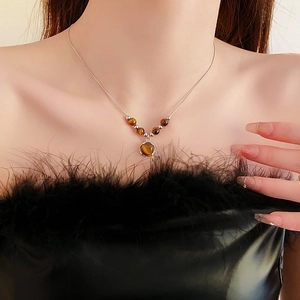 Detail of round brown tiger eye stone pendant necklace worn with vintage outfit