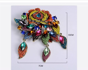 Detail view of colorful rhinestones on a large baroque rose brooch with leaf pendants