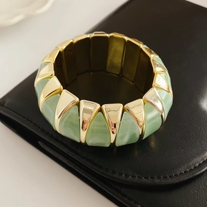 Detail of green geometric rhombic stretch bracelet on a premium black leather texture