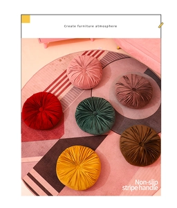 Velvet pumpkin floor cushions in multiple colors arranged on a geometric patterned rug